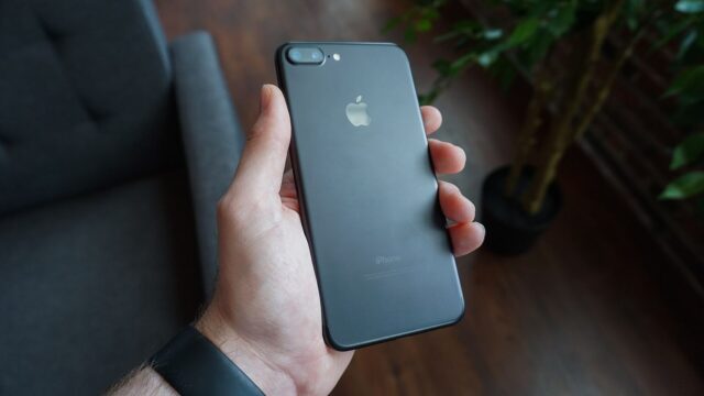 Elinde siyah bir akıllı telefon tutan kişi