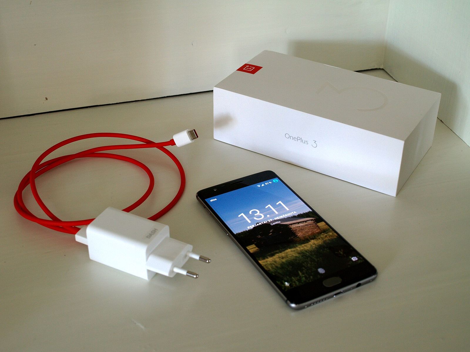 Bir OnePlus telefonu, şarj cihazı ve kutusu bir masanın üzerinde